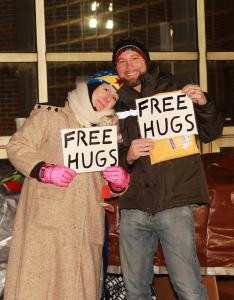 Photo of two people at Gimme Shelter Event holding signs that say "Free Hugs".